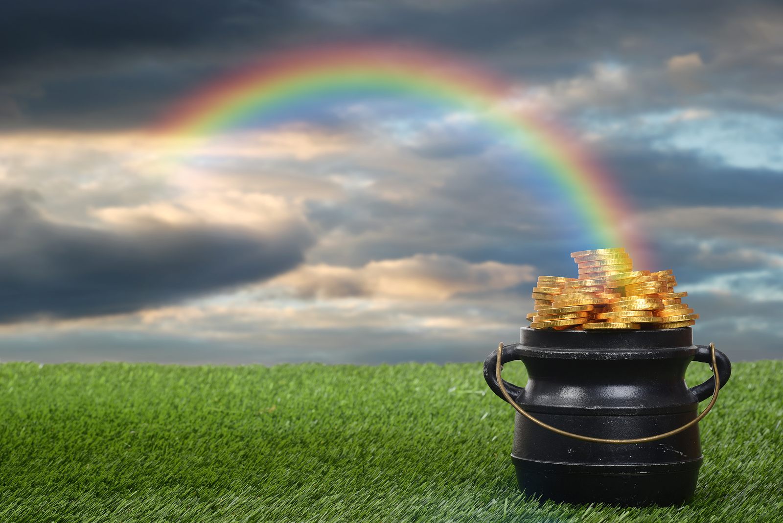 closeup of pot of gold with rainbow with cloudy sky
