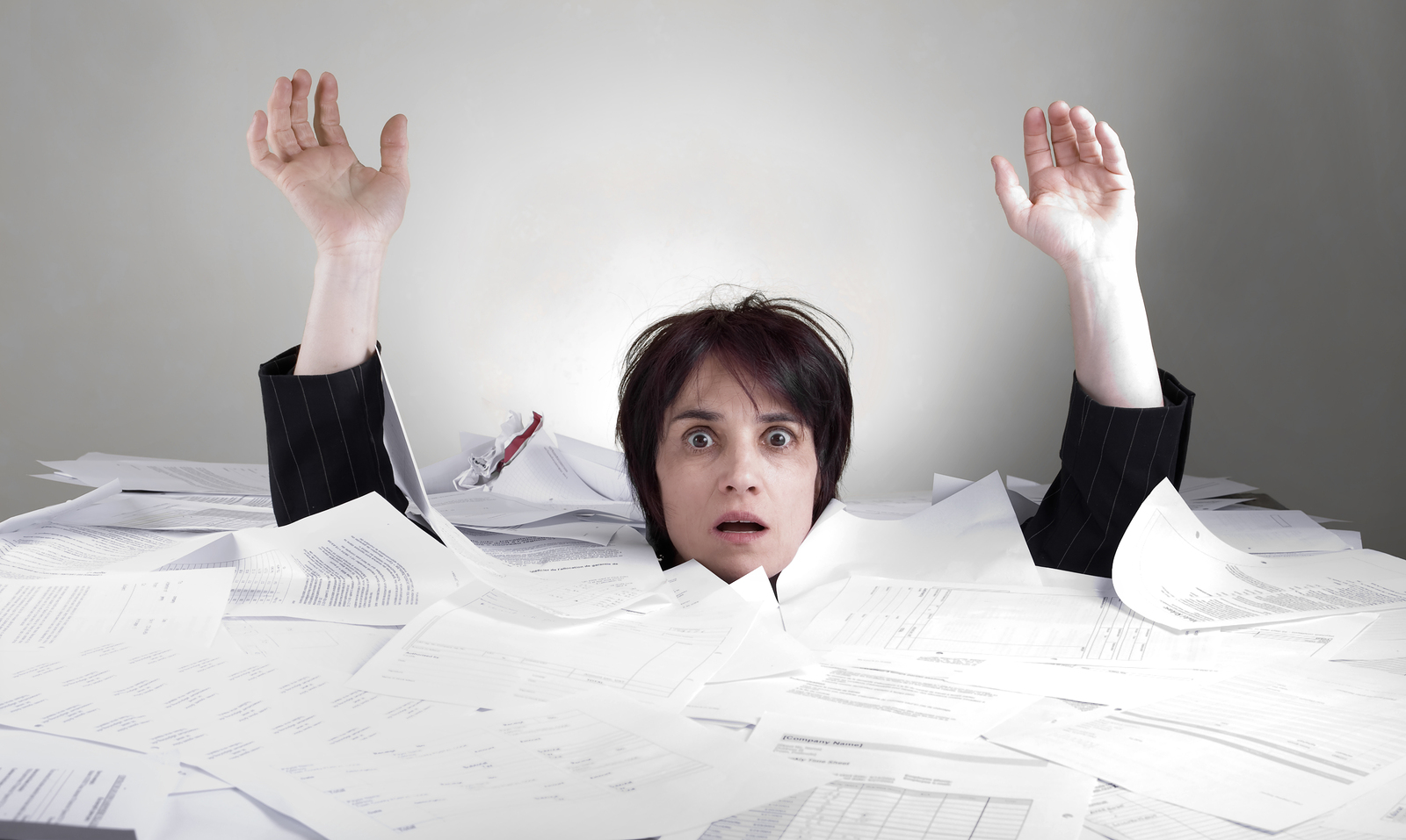 overworked adult business woman buried under paperwork isolated on white
