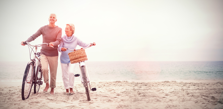 Full length of senior couple with their bicycles at the beach