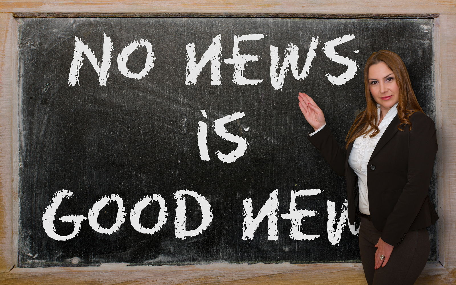 Successful beautiful and confident woman showing No news is good news on blackboard